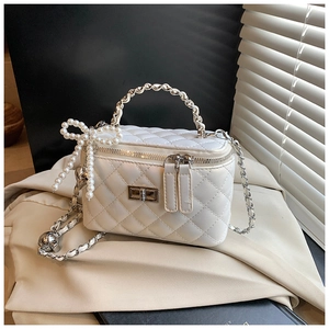 Detail van witte gewatteerde mini box tas met parel strik charme en geweven handvat