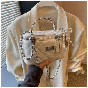 Detail van witte gewatteerde box-tas met parelboog en schedel-hanger aan ketting