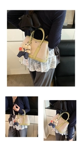 Detailed view of canvas tote bag with green leather trim and cute teddy bear charm accessory