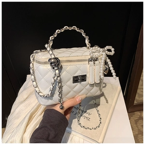 Detail van witte gewatteerde handtas met zilveren sluiting en parelmoeren hanger