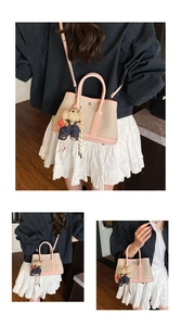 Detail of pink leather trim canvas bucket bag with cute bear charm and shoulder strap
