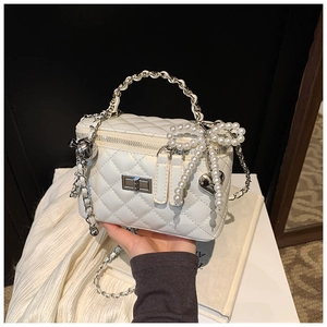 Detail van de witte gewatteerde handtas met parelstrikn en zilveren hart hanger