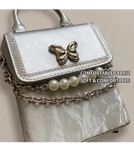 Détail du mini sac argenté plissé avec boucle papillon et décoration de chaîne de perles