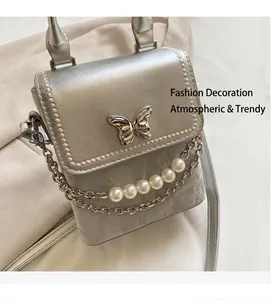 Détail du sac bandoulière argenté avec fermoir papillon et perles décoratives