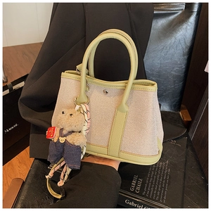 Detail of canvas bucket bag with green leather trim and cute teddy bear pendant
