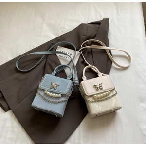 Détail de mini sacs bandoulière avec boucle papillon en métal et chaîne de perles