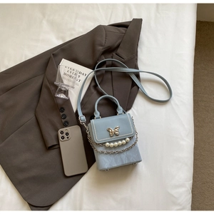 Détail du sac bleu clair avec boucle papillon dorée et bordure en perles blanches