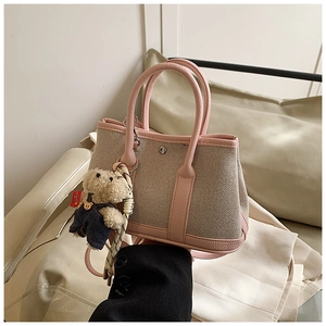 Detail of pink leather trim canvas tote with cute teddy bear charm and round handles