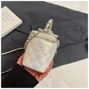 Detail van witte gewatteerde box-tas met parelmoerglans en parelketting handvat