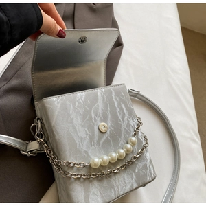 Détail du sac bandoulière argenté avec chaîne de perles et fermeture magnétique