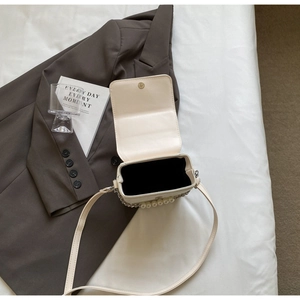 Détail du mini sac blanc cassé avec poignée en perles et fermeture magnétique