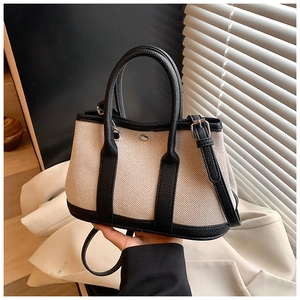 Detail of canvas and leather tote bag showing detachable shoulder strap and handle