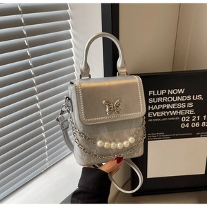 Détail du sac bandoulière argenté avec fermoir papillon et chaîne en perles élégante