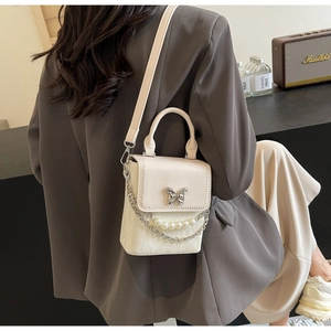 Détail du sac crème élégant avec fermoir papillon 3D et accents de chaîne en perles