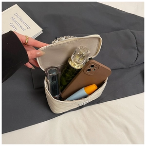 Binnenzicht van beige gewatteerde boxtas met ketting met cosmetica en mobiele telefoon
