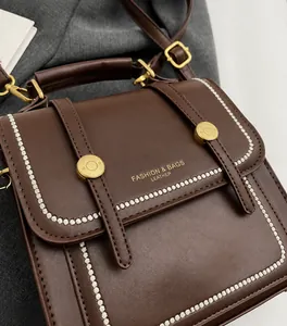 Detalle del bolso de cuero marrón con costuras onduladas blancas y hebillas doradas