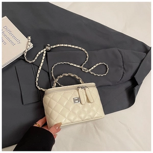 Detail van gewatteerde beige schoudertas met kettingriem en zilveren draaisluiting