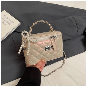Detailweergave van beige gewatteerde boxtas met parelhandvat en metalen ketting