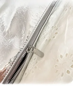 Detail of metallic silver dumpling bag showing wrinkled texture and metal zipper closure