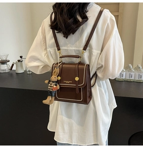 Detalle de la mochila vintage marrón oscuro con hebilla dorada y colgante de conejo
