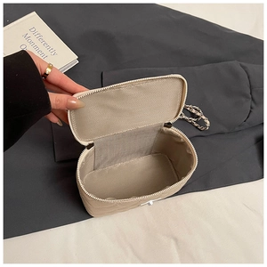 Macro-opname van beige gewatteerde tas met zilveren ketting en V-vormige stoffen voering