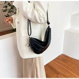 Detail of black dumpling bag with pleated texture and silver sphere pendant decoration
