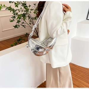 Detailed close-up of a silver crescent moon shoulder bag with textured pleats and metal knot charm