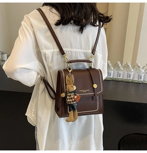 Primer plano de mochila vintage marrón con costuras blancas y amuleto de conejo