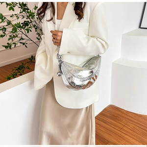 Detail of silver metallic crescent bag with knotted chain strap on a white blazer