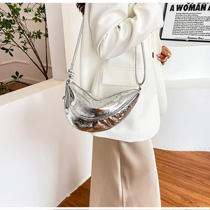 Detail of silver metallic crescent bag with pleated texture and stylish knot on strap