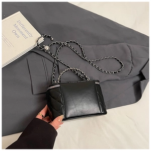 Detail van zwarte gewatteerde box-tas met zilveren ketting en metalen ritssluiting