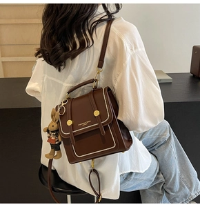 Detalle de mini mochila de cuero marrón retro con costuras blancas y colgante conejo