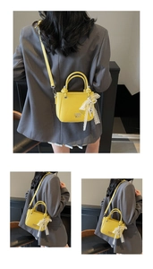 Detail van gele lederen bucket bag met kanten strik en parelmoer hanger accenten