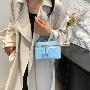 Light blue quilted mini bucket bag with gold chain strap shown on a beige trench coat