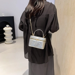 Silver quilted mini bucket bag with gold chain strap and top handle on a model back