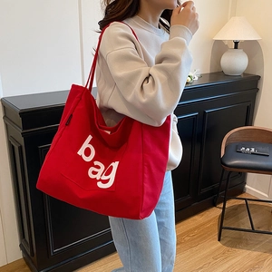 Large red canvas tote bag with white bag lettering print and wide shoulder strap