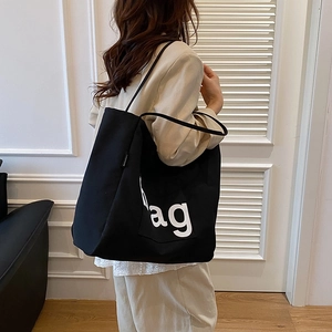 Chic black canvas tote bag with ag letter print shown in a stylish street style shot