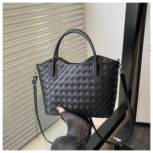 Gros plan du sac cabas tissé noir avec texture croisée et détails métalliques argentés