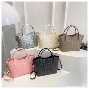 Détail de sacs cabas tissés en argent, beige et noir avec bandoulières amovibles