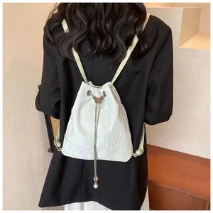 Detail of light green drawstring backpack with metal butterfly lock and pearl charms