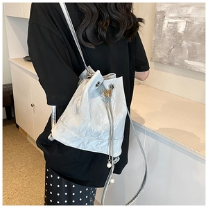 Detail of silver bucket bag with metallic butterfly accent and pearl drawstring pendant