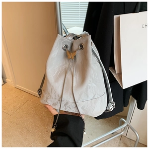Detail of light gray drawstring bucket bag with gold butterfly clasp and pearl charms