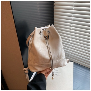 Close-up of creamy bucket bag featuring pleated leather texture and butterfly buckle