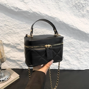 Quilted black mini bucket bag with gold chain strap and top handle in a modern setting