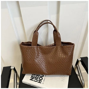 Detail of dark brown leather woven tote bag showing premium grid texture and dual handles