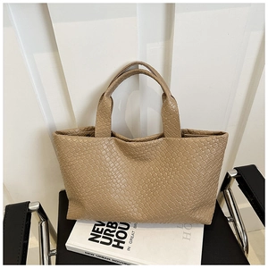 Detail of woven khaki tote bag featuring premium interlaced texture on a leather handle bag