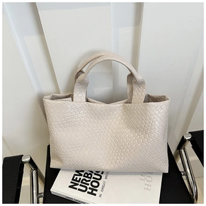 Close-up of the woven leather texture and Intrecciato pattern on the beige tote bag