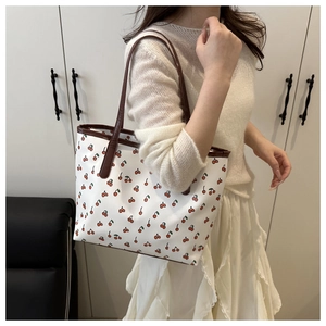 Interior view of white cherry print tote bag with brown faux leather trim on shoulder
