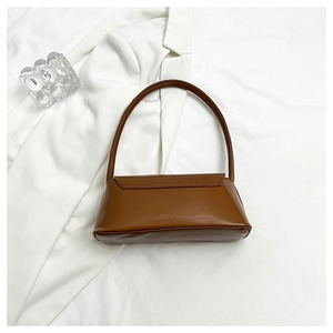Chic brown patent leather underarm bag on soft white fabric with glass decor
