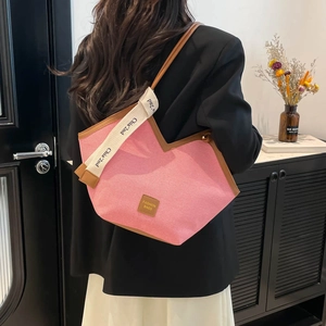 Pink canvas tote bag with brown leather trim and fashion strap shown on model's shoulder